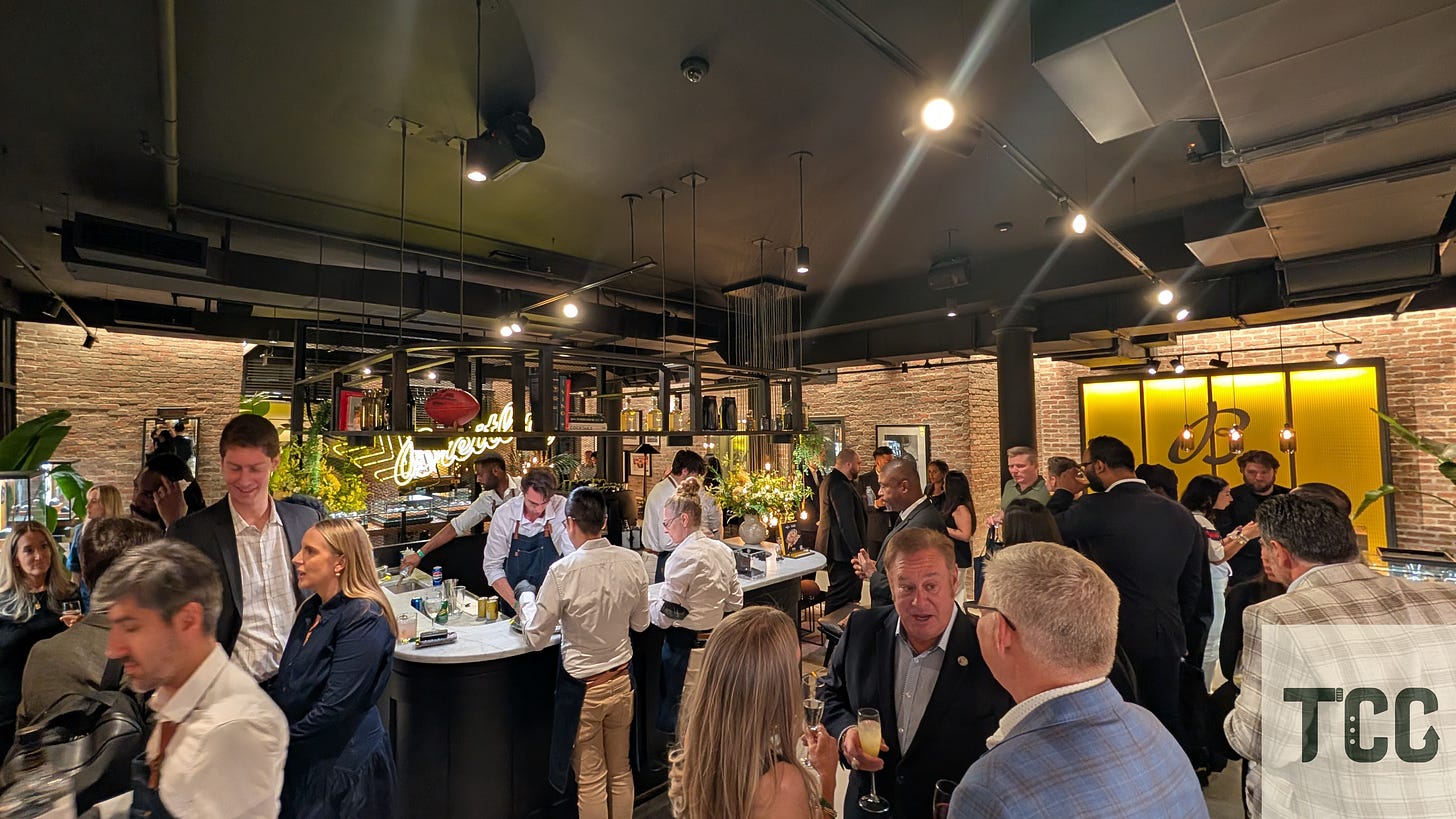 Inside the Breitling boutique in NYC’s Meatpacking District, bartenders serve cocktails under warm lighting while guests mingle. A glowing neon sign reads "Breitling" in the background.
