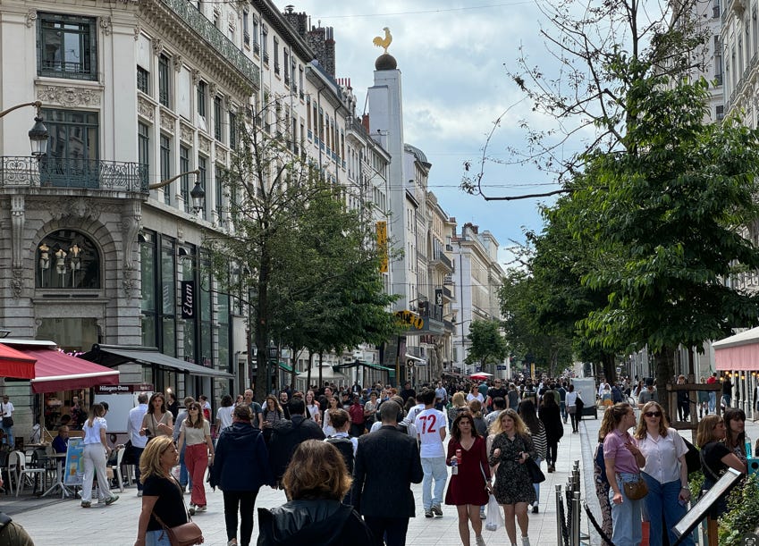 A group of people walking on a sidewalk

Description automatically generated