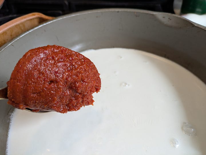 Coconut cream pouring into panang curry base. Panang curry paste just before mixing with coconut cream.