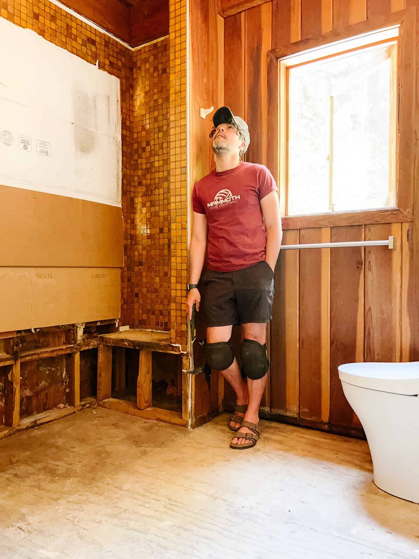 Anthony standing ina gutted bathroom with the tub and picture window removed. 