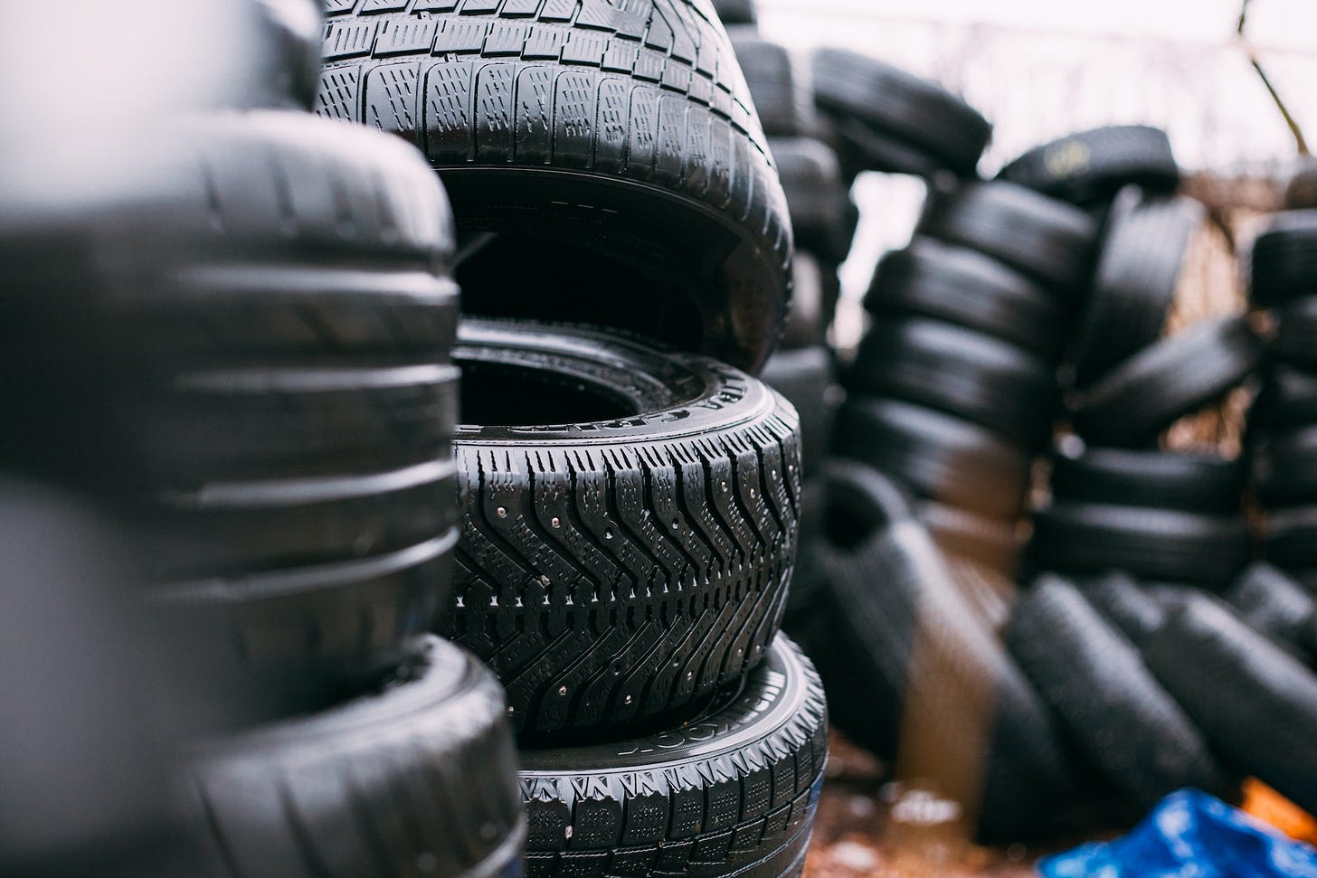 A stack of tires sit in a tired yard. A stack of tires sit in a tired yard.