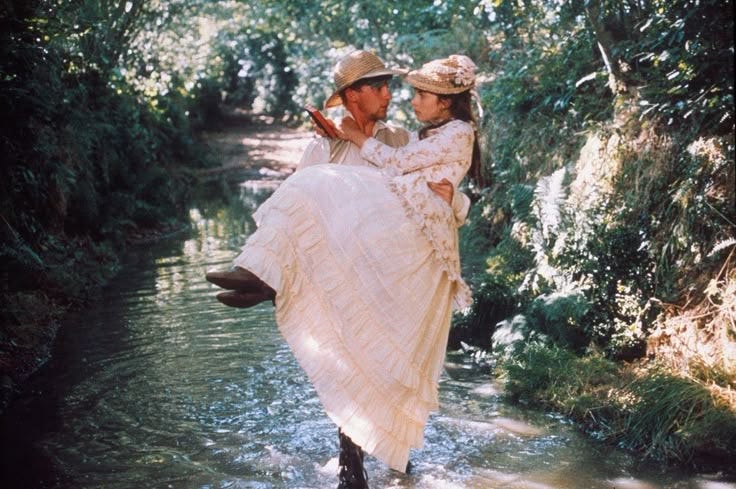 This may contain: a man carrying a woman across a river