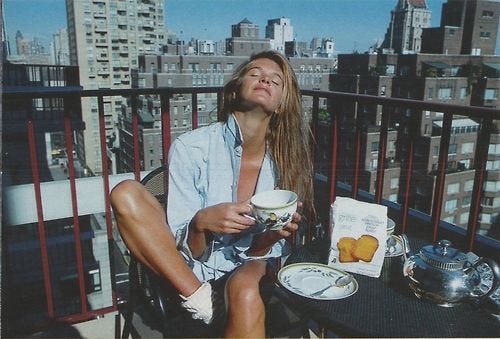 This may contain: a black and white photo of a woman sitting at a table on a balcony eating food