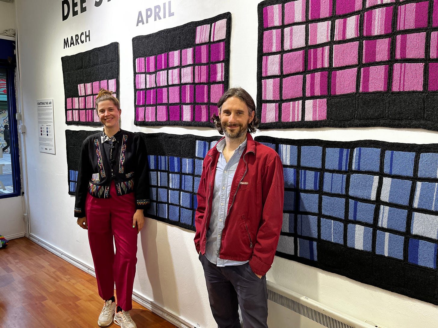 Two people in front of knitting showing air quality data