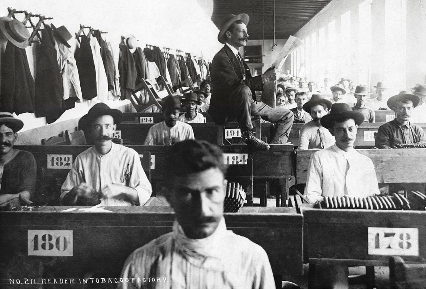 A hired reader reads to cigar makers hard at work in Cuban cigar factory, ca. 1900-1910