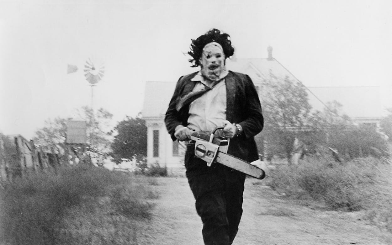 Black-and-white still of Gunnar Hansen as Leatherface, chainsaw in hands. 
