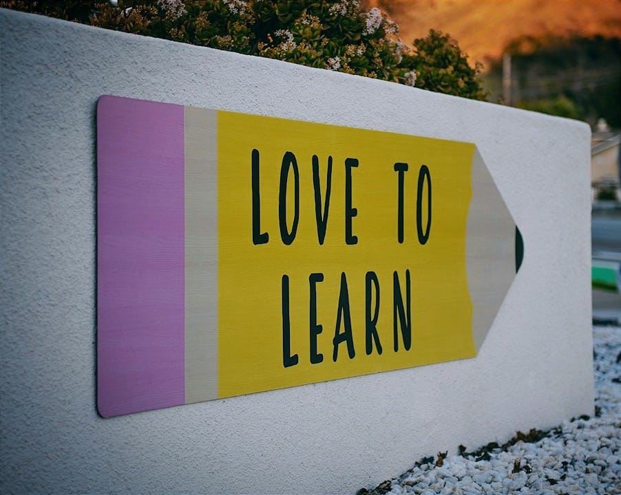 love to learn pencil signage on wall near walking man