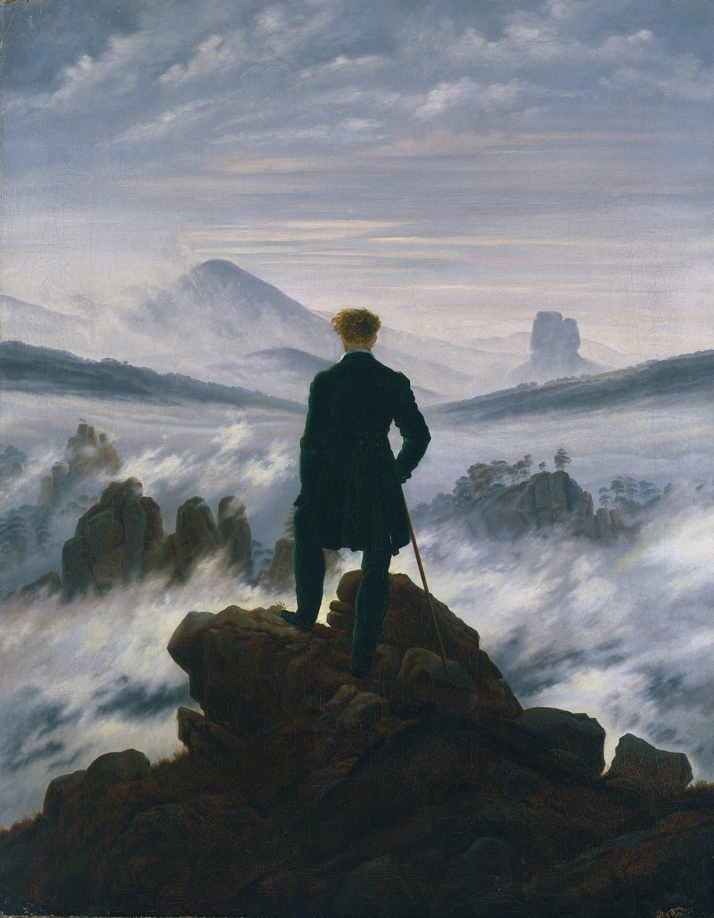 Caspar David Friedrich’s Wanderer Above the Sea of Fog, showing a man in a dark coat standing on a rocky peak and looking across mist-covered mountains.