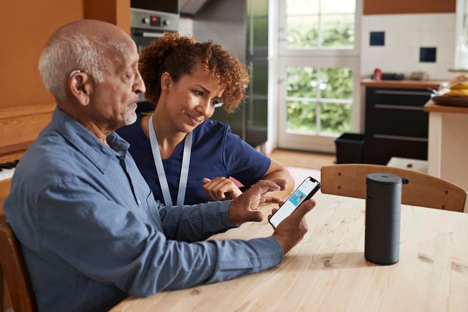 Nurse teaching senior man to book online appointment
