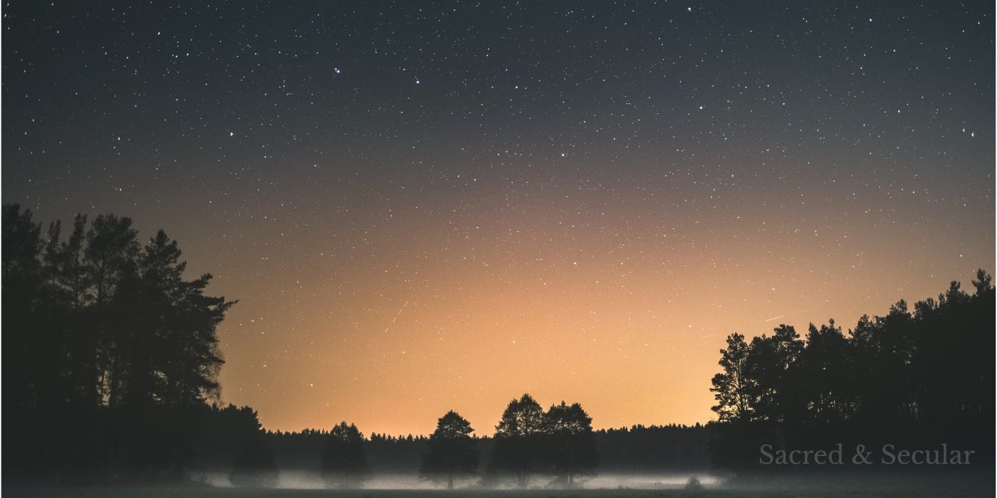 A star-filled night sky stretches above a dark tree-lined horizon, with a warm golden glow rising in the distance and mist hovering over still water. A star-filled night sky stretches above a dark tree-lined horizon, with a warm golden glow rising in the distance and mist hovering over still water.