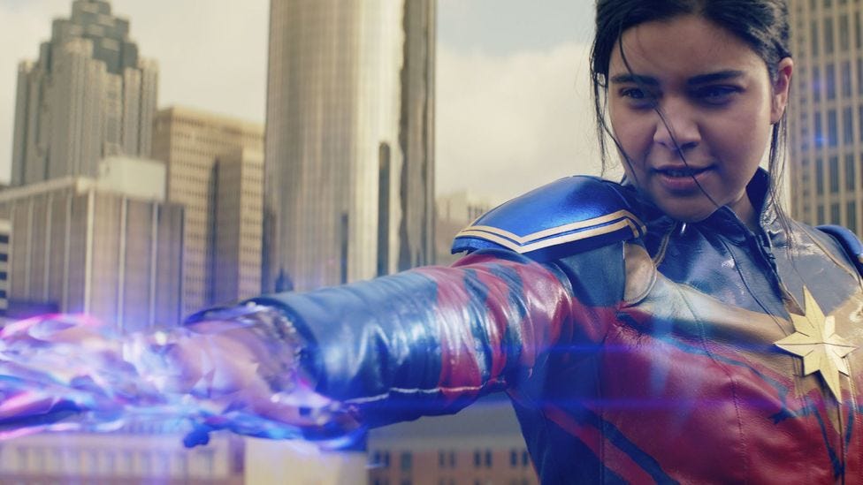 Image of Ms. Marvel in full costume blasting her powers out of her hands with skyscrapers in the background (Credit: Marvel Studios 2022) Image of Ms. Marvel in full costume blasting her powers out of her hands with skyscrapers in the background (Credit: Marvel Studios 2022)