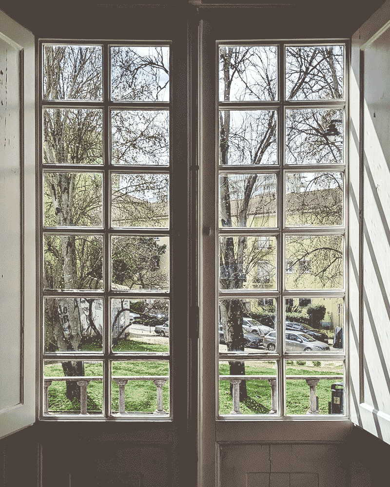 A GIF of two photos of windows looking out to the same landscape. In one photo, it is sunny, and in the other, it is rainy.
