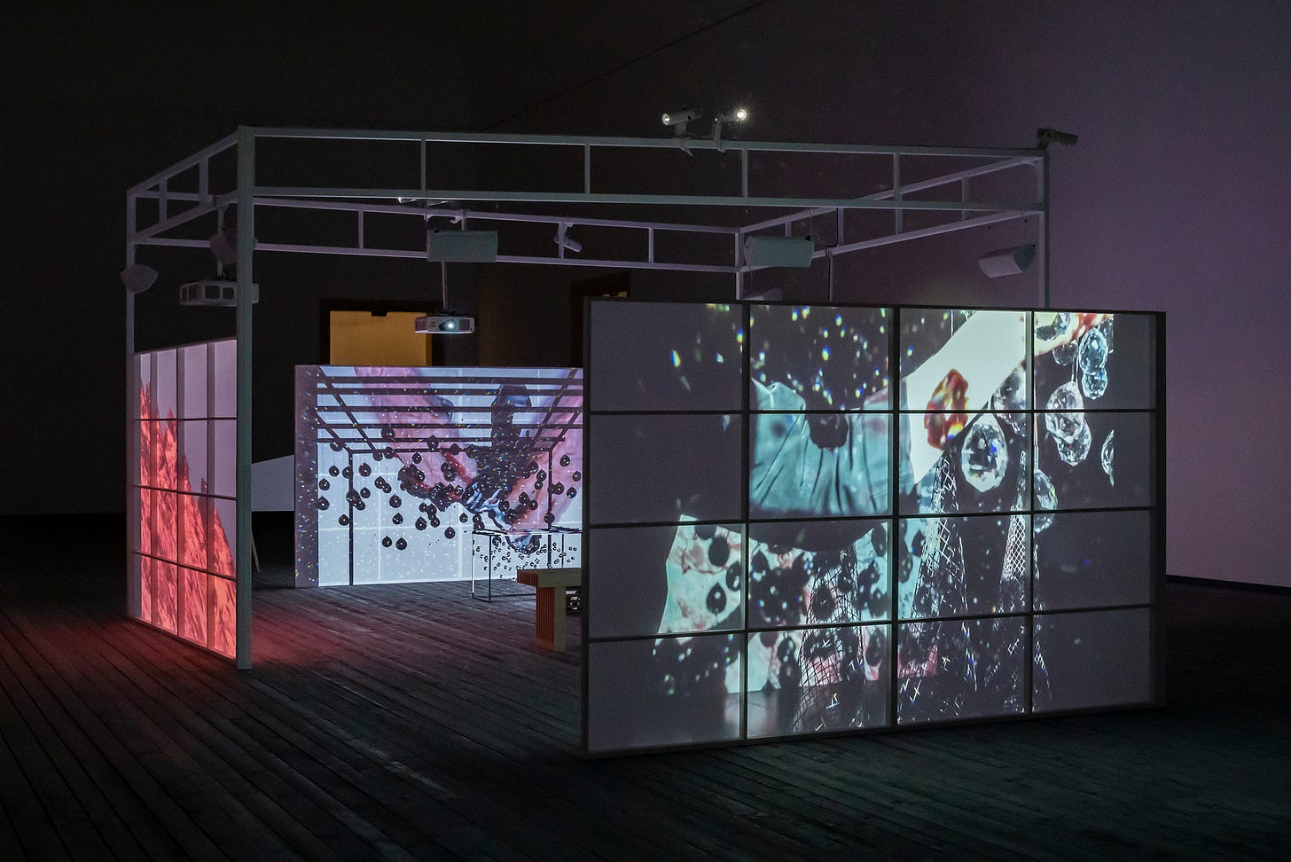 A Joan Jonas installation: scaffolding with screens on showing images that look like blobs or balloons