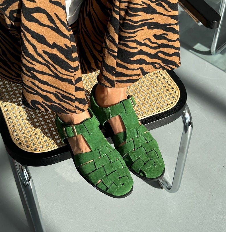 May include: Green suede woven flat sandals with buckle closure. The sandals have an open-toe design and a comfortable, low heel.  These summer shoes are perfect for warm weather and casual outfits.