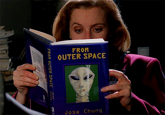 Scully sits at her desk reading "From Outer Space" by author Jose Chung. The book has a drawing of a gray alien on the cover. Scully sits at her desk reading "From Outer Space" by author Jose Chung. The book has a drawing of a gray alien on the cover.