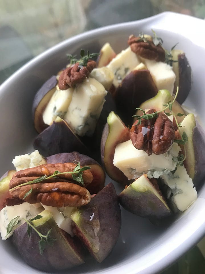 figs stuffed with blue cheese and pecans ready to be baked in a white dish Plus baked ones