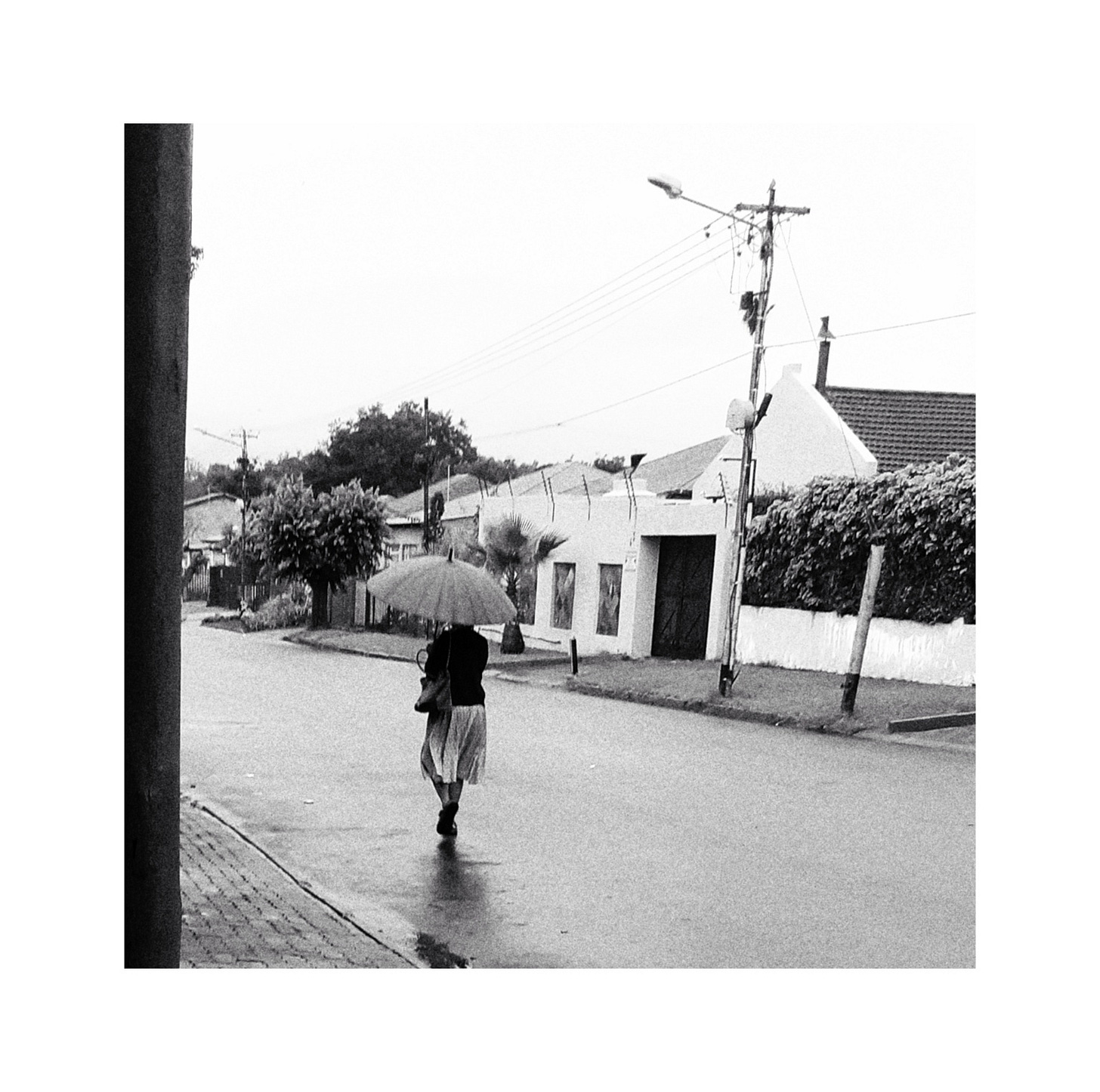 A woman walking with an umbrella down a street.