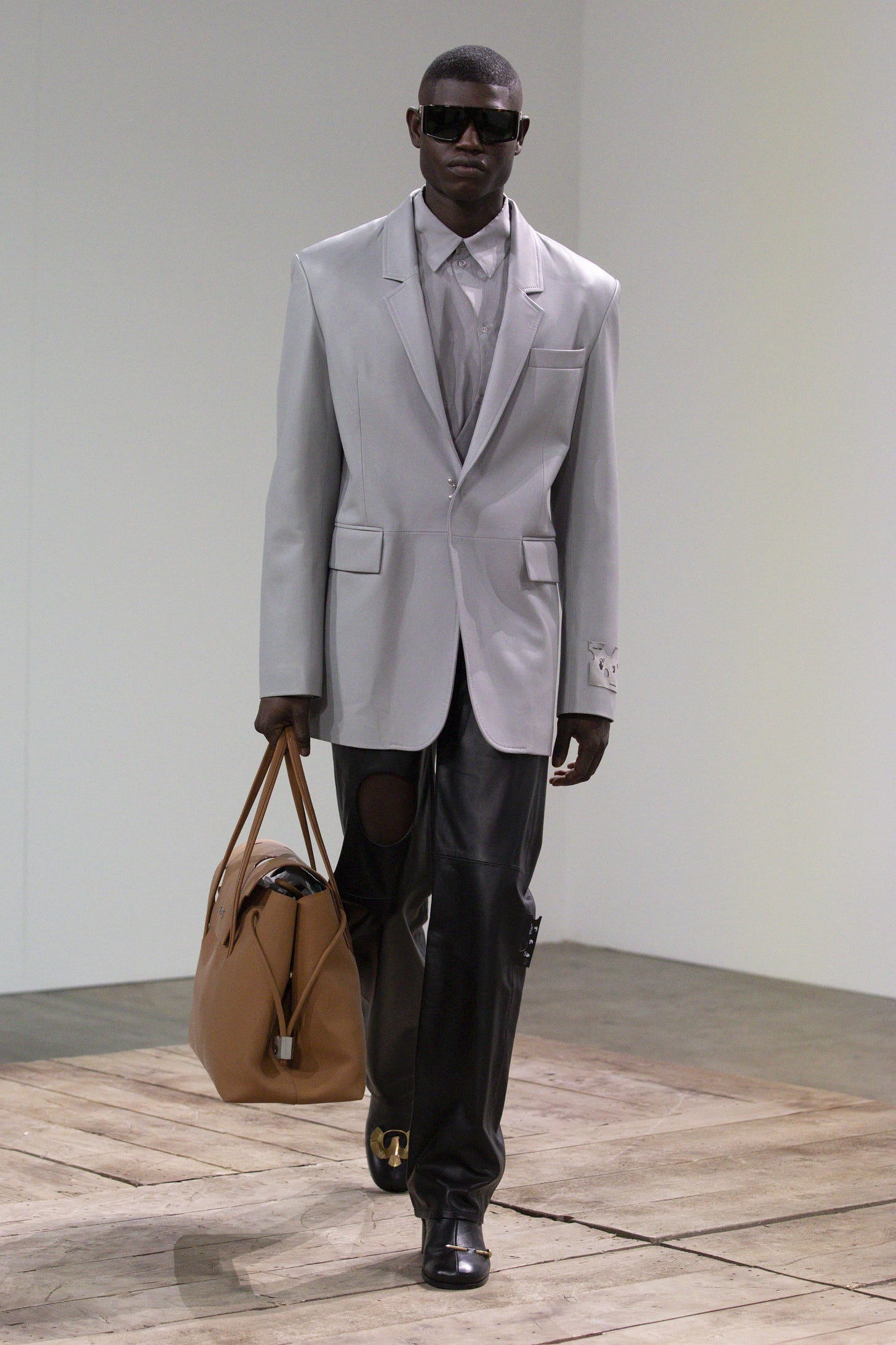 Image may contain Clothing Apparel Suit Coat Overcoat Sunglasses Accessories Accessory Tuxedo Human and Person