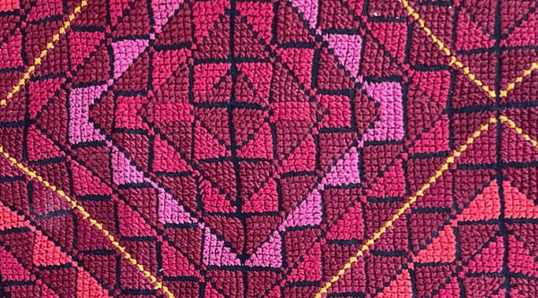 Close up photograph of pink embroidery in a chevron-based geometric design