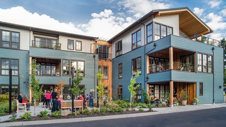This may contain: a group of people standing in front of two story apartment buildings with balconies