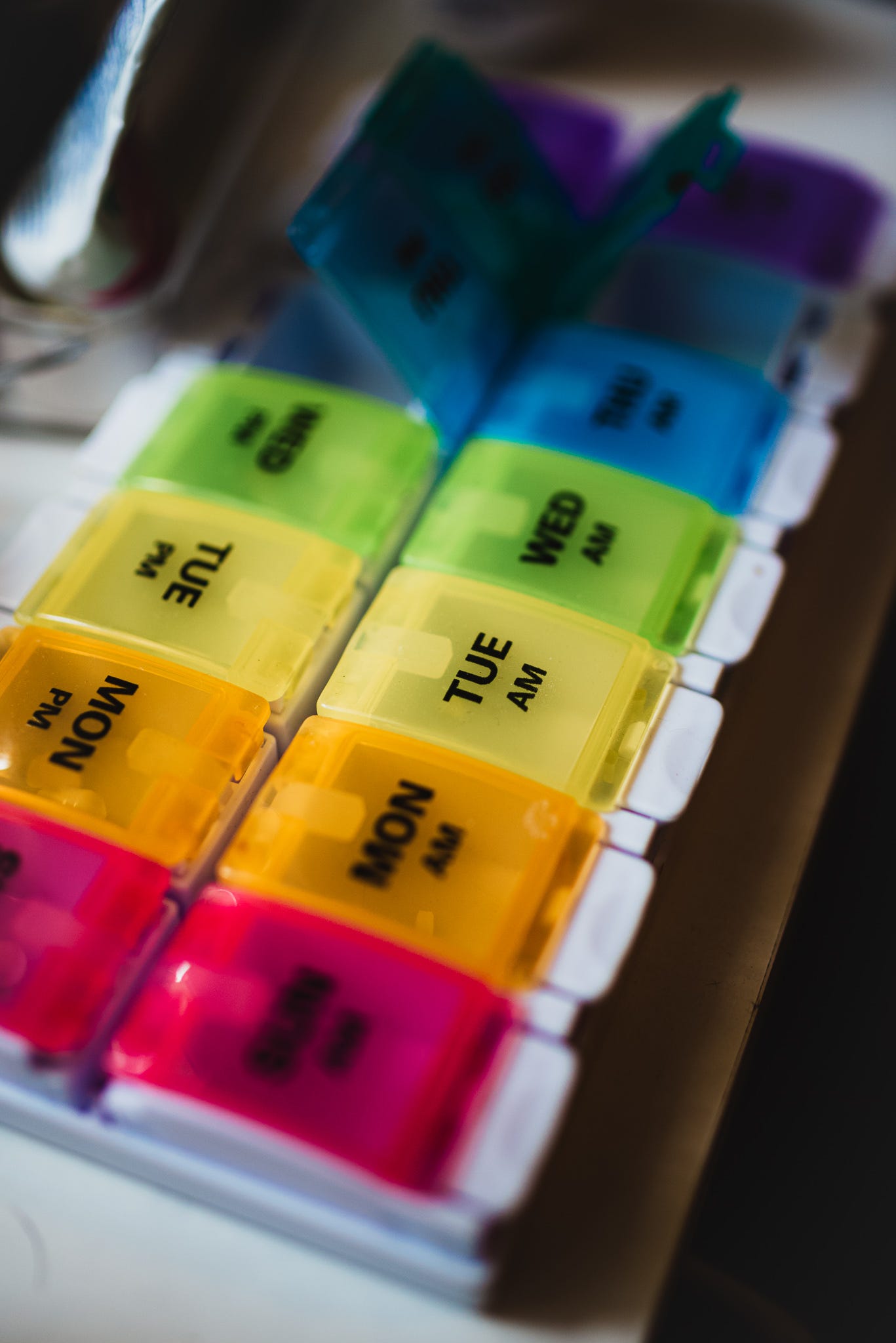 A rainbow colored daily pill case with a couple compartments open. A rainbow colored daily pill case with a couple compartments open.