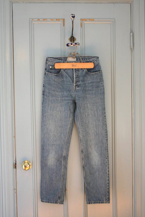 Three pairs of pants pictured; from left to right black jeans, blue jeans, brown pants