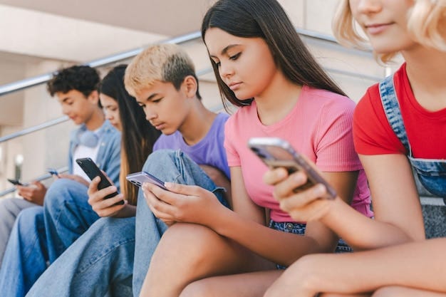 Group of teenagers holding mobile phones watching video communication online sitting on the street | Premium Photo Group of teenagers holding mobile phones watching video communication online sitting on the street | Premium Photo