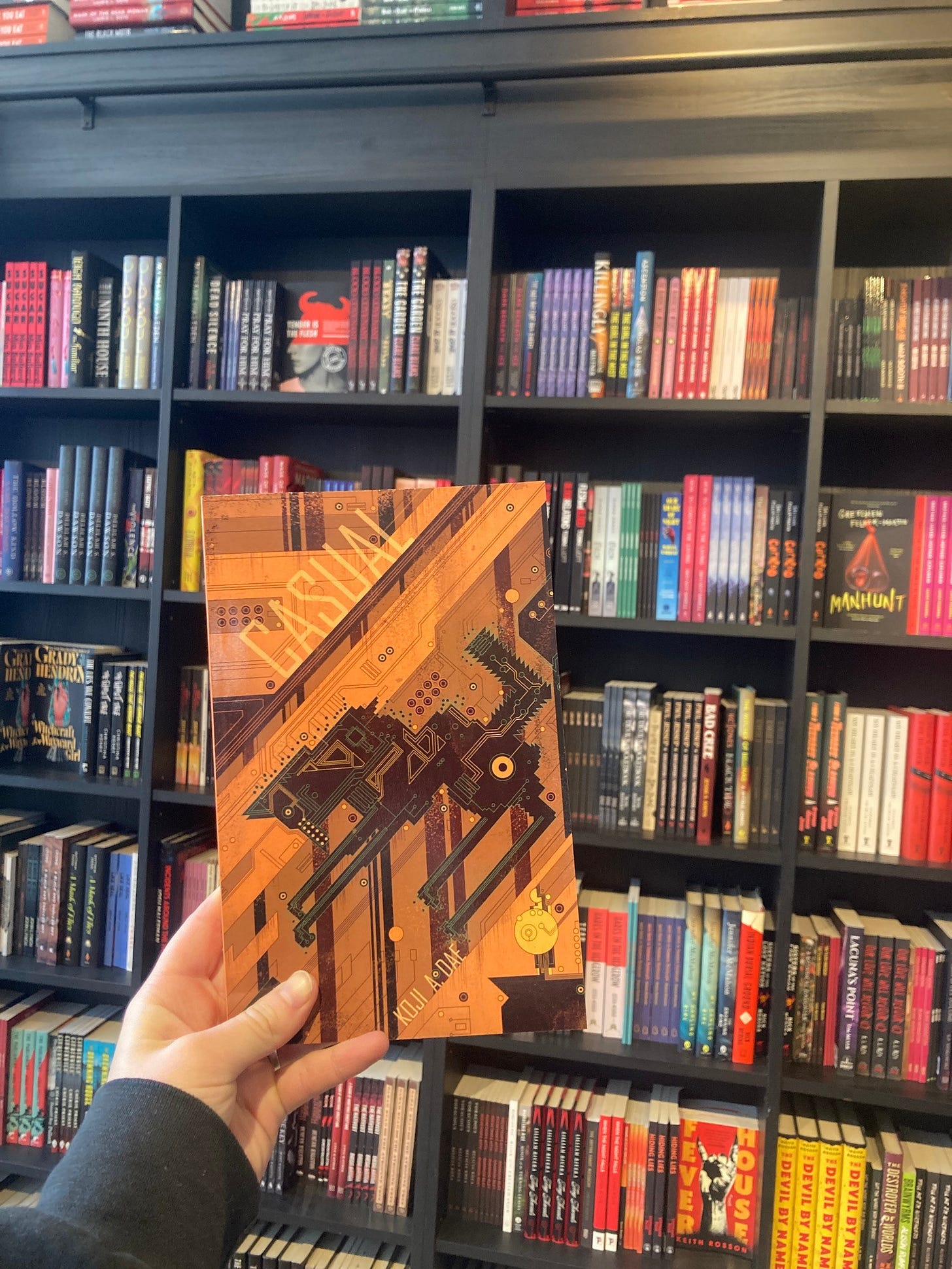 CASUAL by Koji A. Dae in front of the shelves at Little Ghosts Books