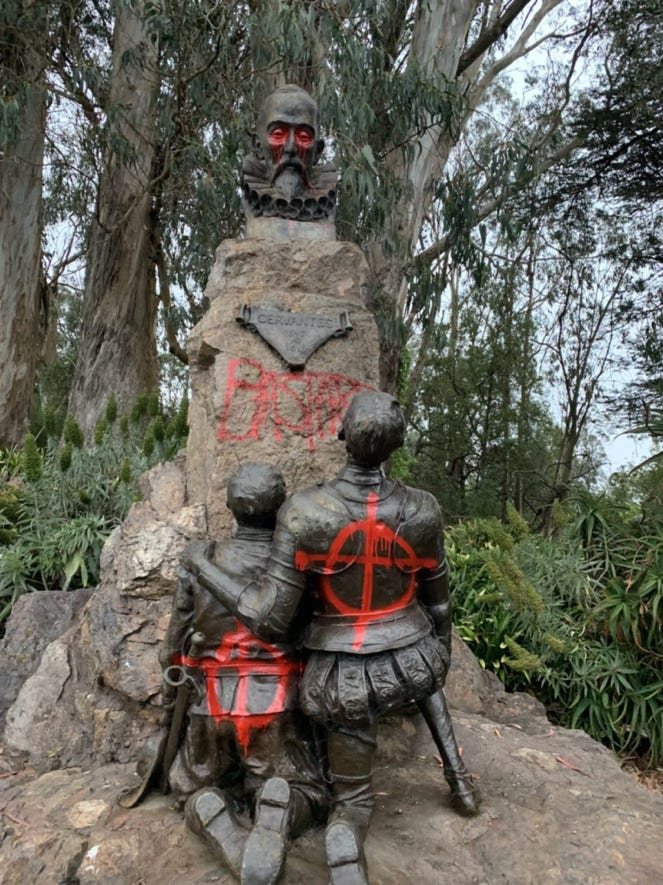 A statue of two men with red paint on it

AI-generated content may be incorrect.