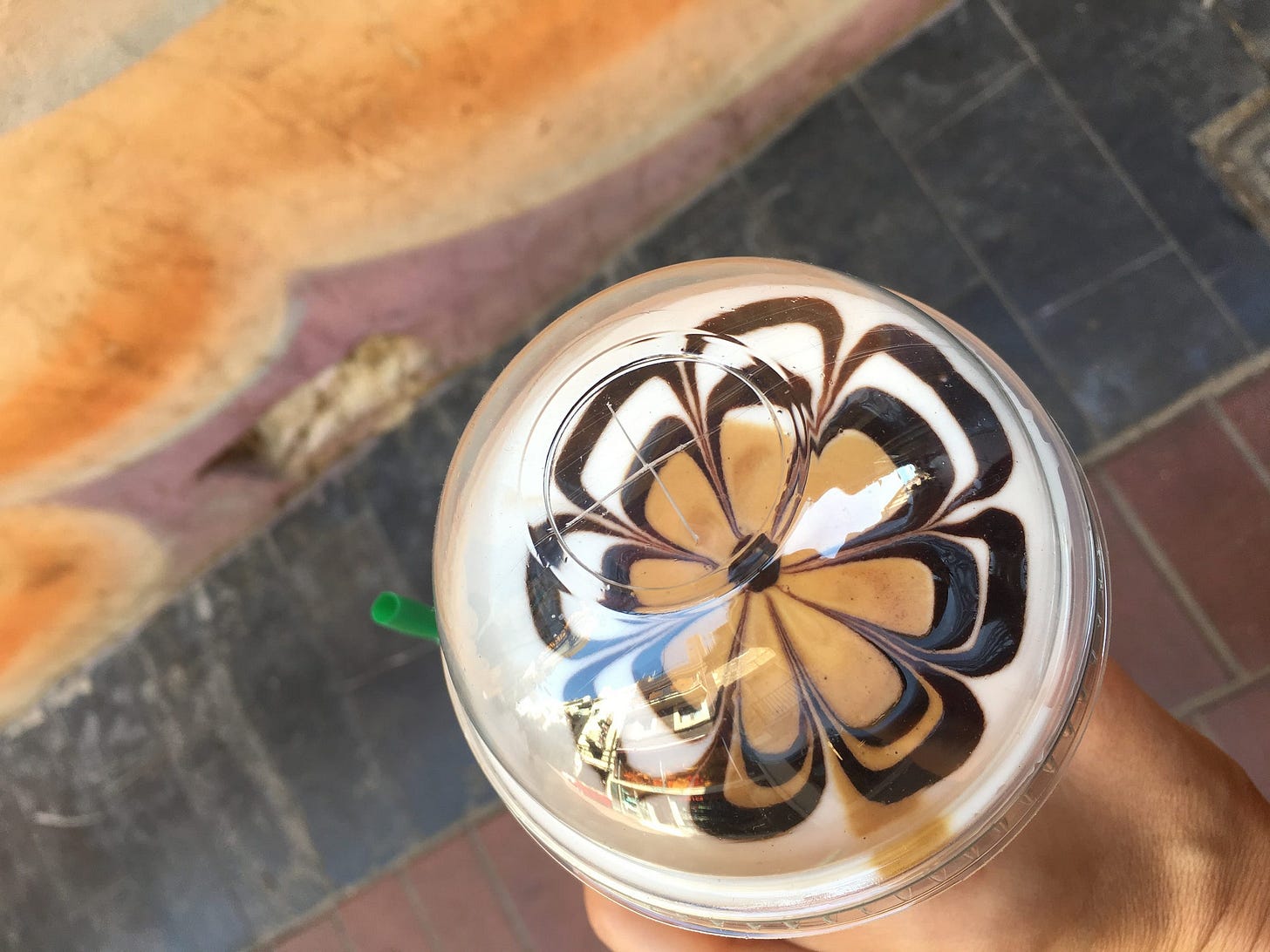 a man holds a coffee with a floral pattern hand-crafted in the foam