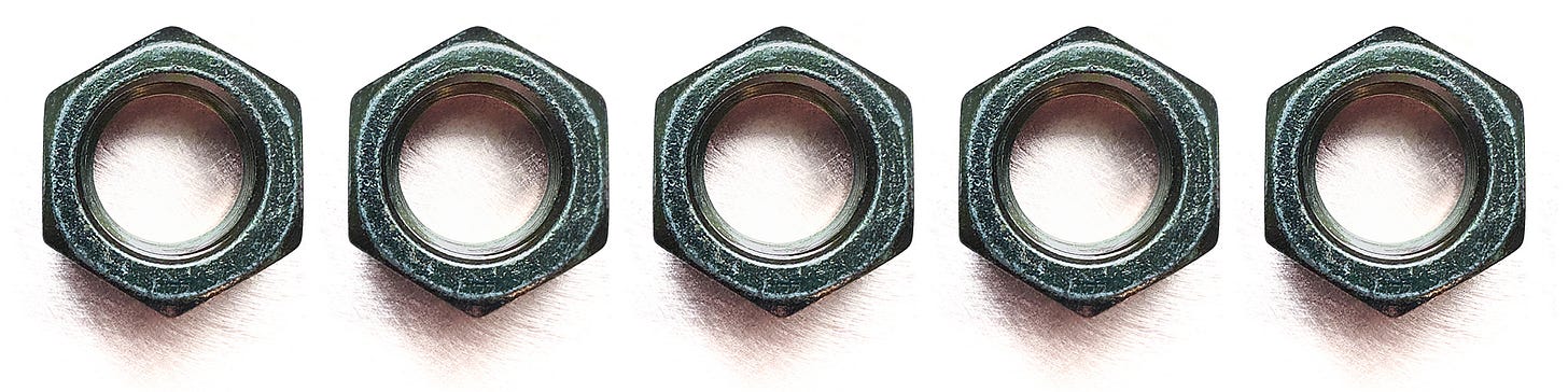 Photograph of five metal nuts arranged in a straight line on a white background.