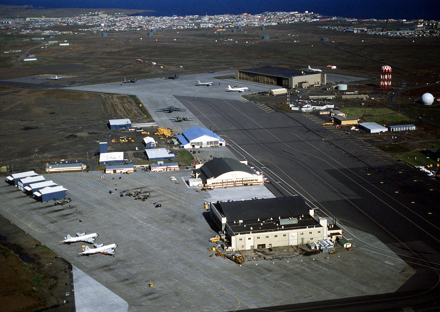 An aerial view of the ramp areas and facilities of the 57th Fighter Interceptor Squadron, with other facilities in the background.