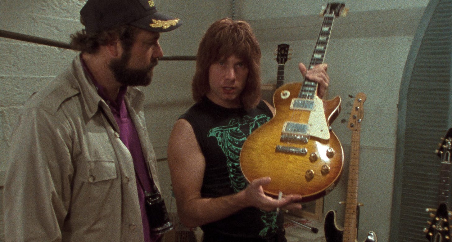 This Is Spinal Tap | Still features Rob Reiner as Marty DiBergi and Christopher Guest as Nigel Tufnel, with Nigel showing off a guitar.