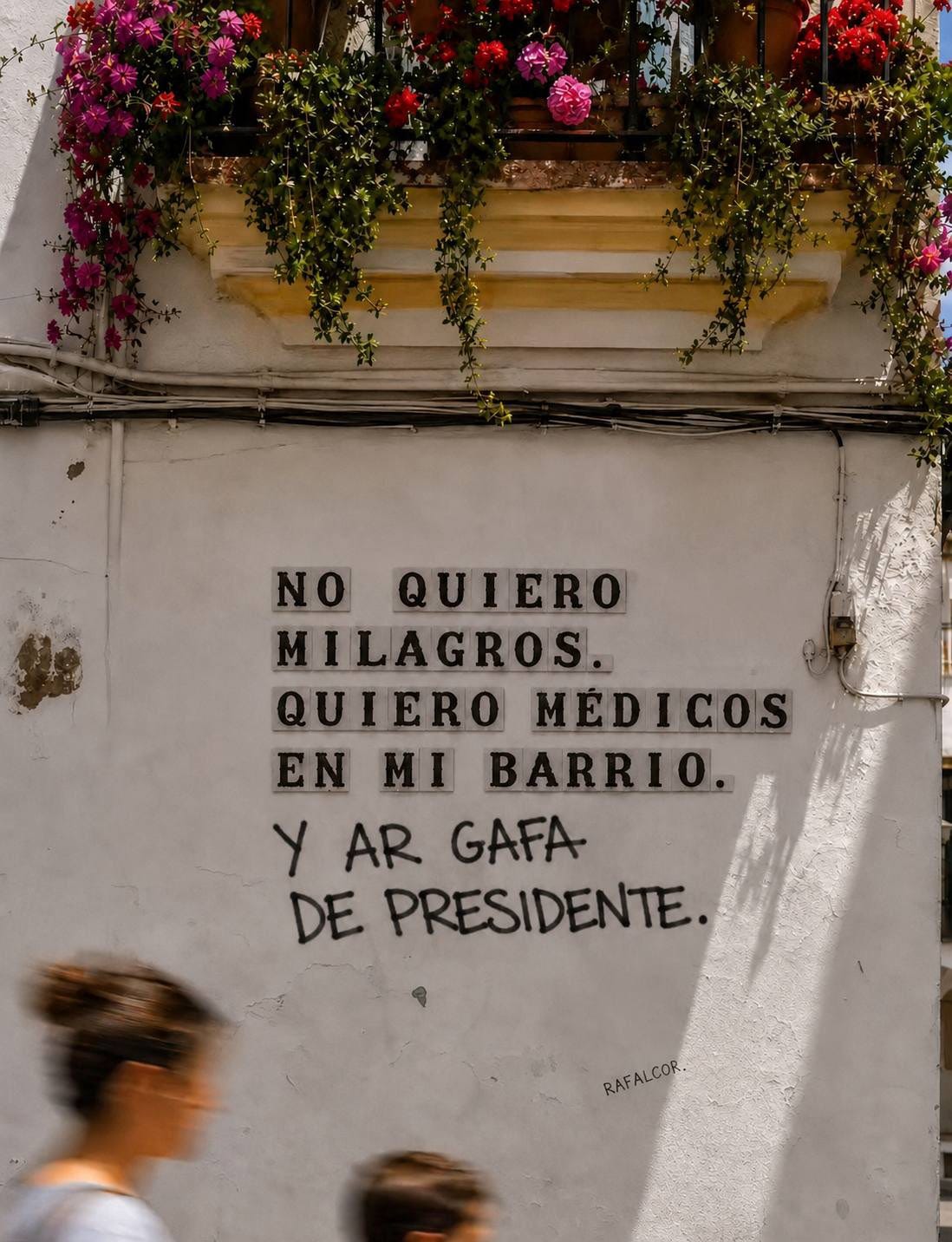 Un muro bianco sotto un balcone fiorito con una scritta in piastrelle che recita "No quiero milagros. Quiero médicos en mi barrio." seguita da una scritta a mano con "Y al Gafa de presidente.". Un muro bianco sotto un balcone fiorito con una scritta in piastrelle che recita "No quiero milagros. Quiero médicos en mi barrio." seguita da una scritta a mano con "Y al Gafa de presidente.".