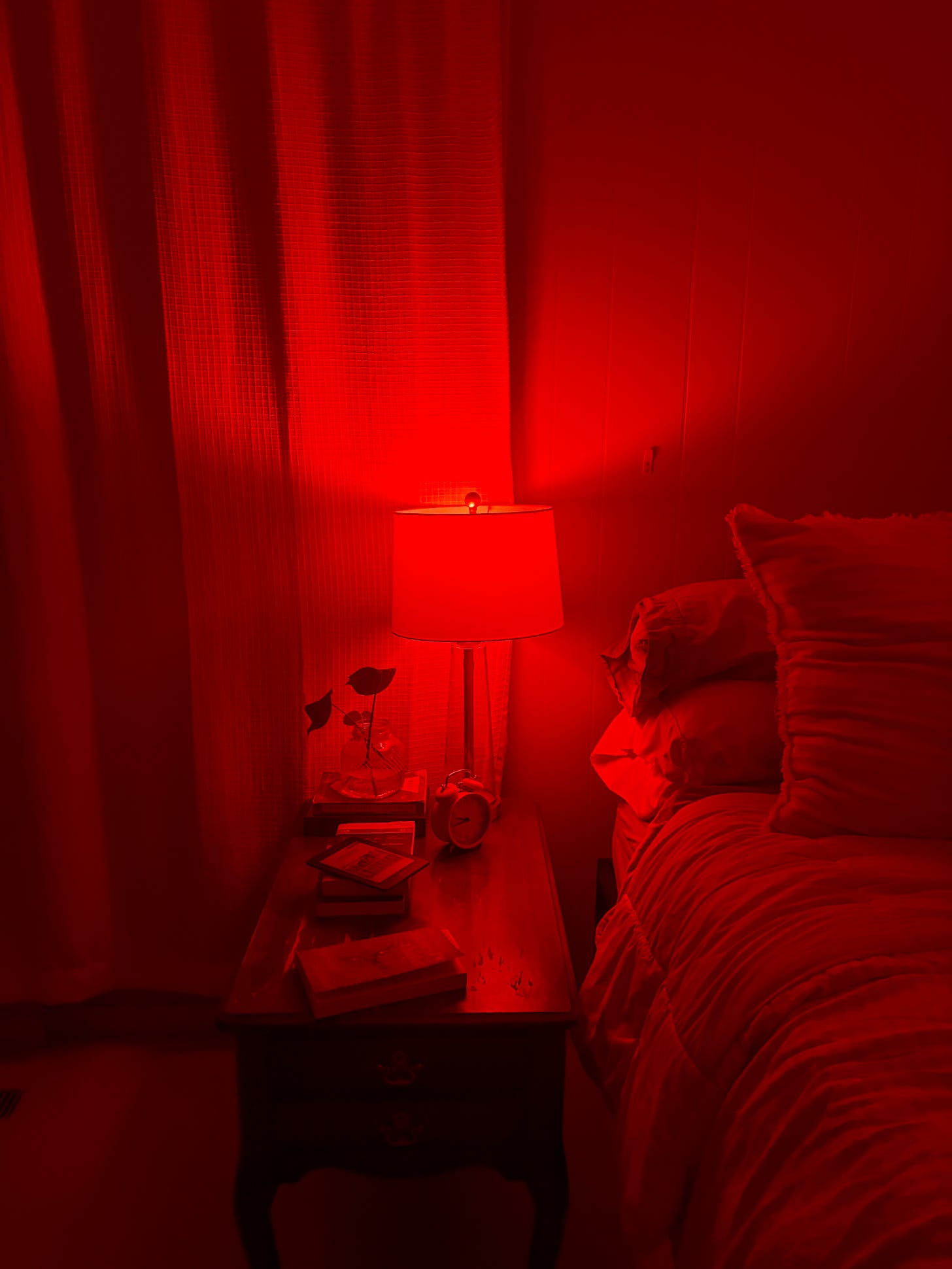 red light bulb on bed side table with books 