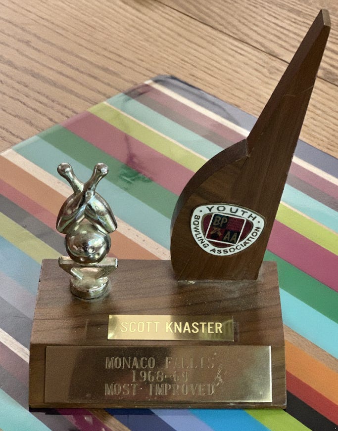 A small bowling trophy. The tags read "Scott Knaster / Monaco Fallis / 1968-69 / Most Improved". There's a lovely little sculpture of a ball and two pins, which I think is the BPAA logo. Also the Youth Bowling Association insignia.