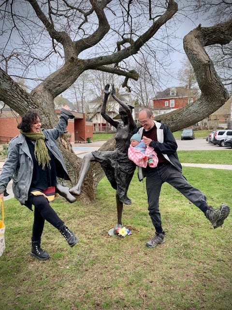 A grandmother, son and grandchild dance in front of a statue of Mona Parsons in Wolfville, Nova Scotia