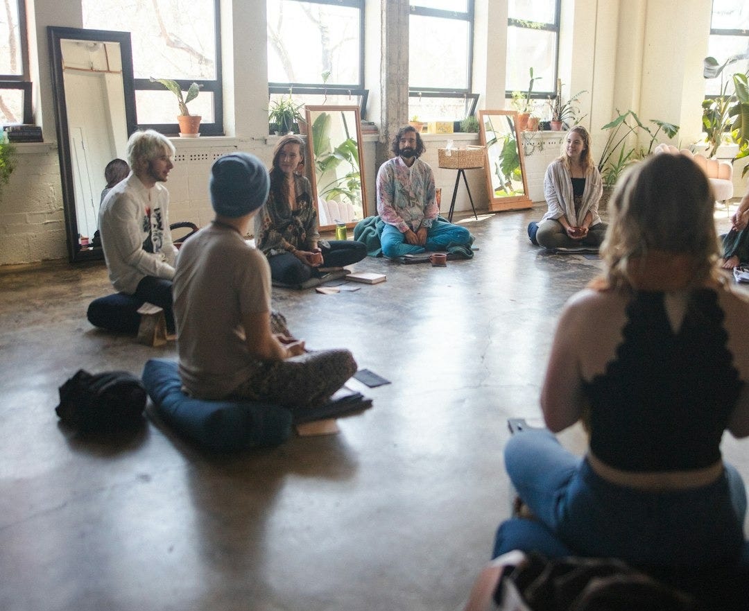 a group of people sitting on the floor in a room a group of people sitting on the floor in a room