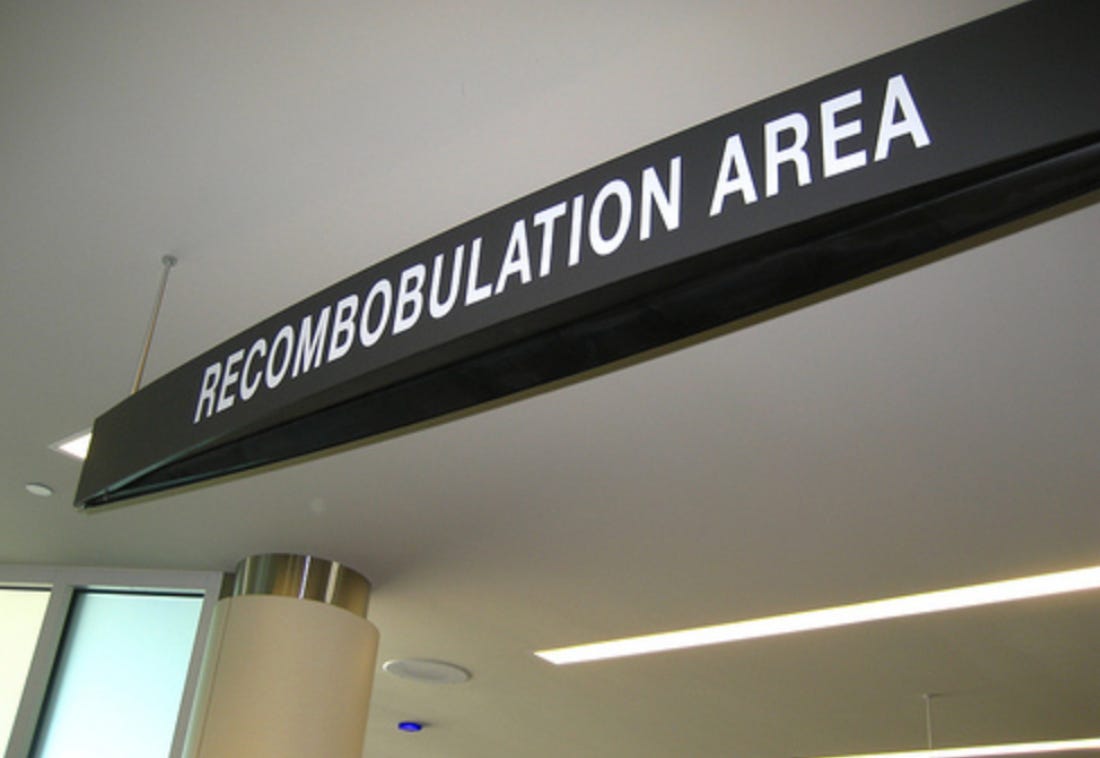 Photo of sign at an airport that reads "RECOMBOBULATION AREA".
