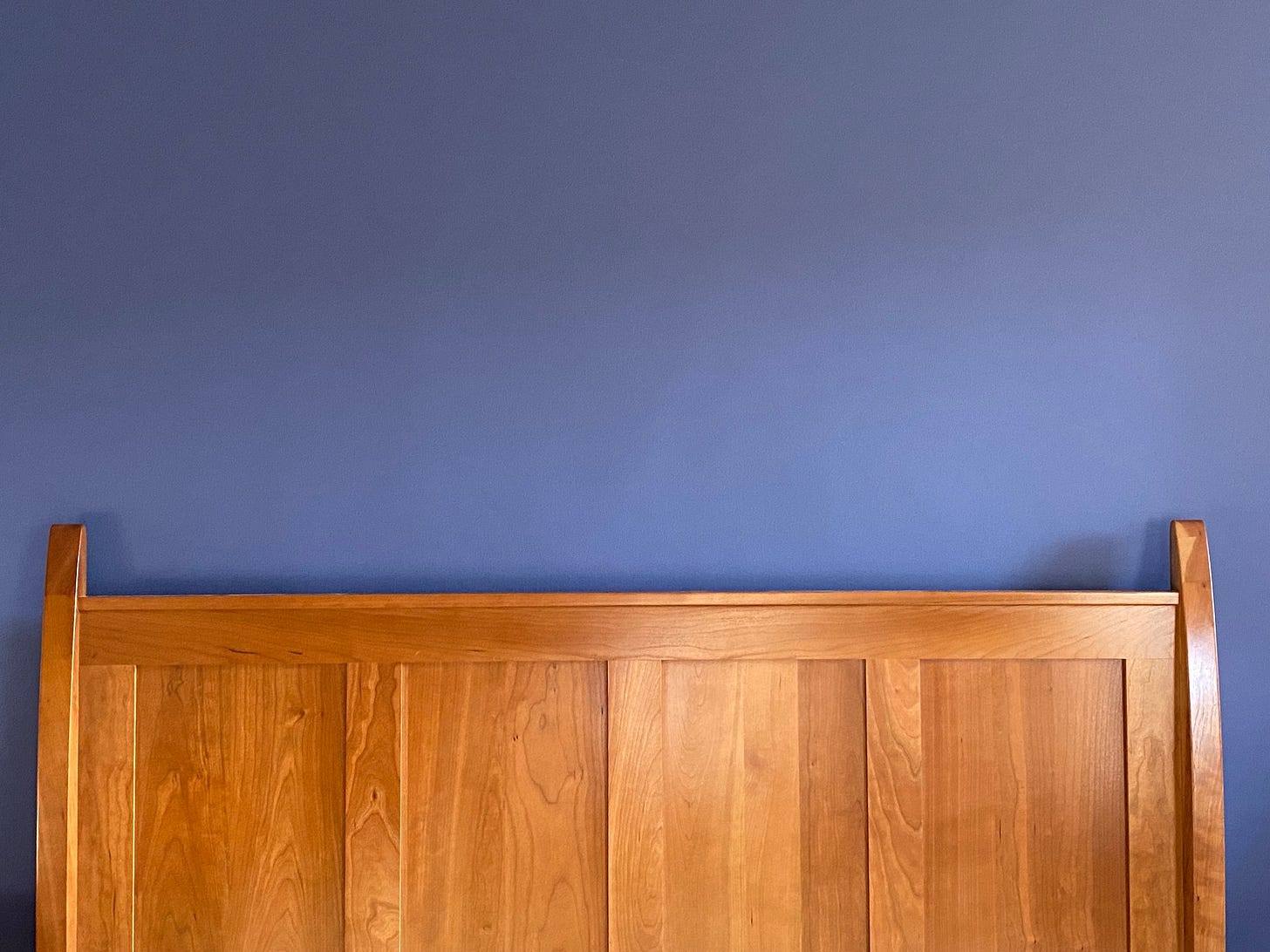 Cherry headboard against blue wall.