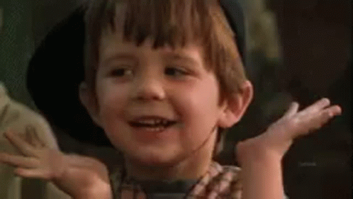 a young boy wearing a cowboy hat is making a funny face with his hands in the air . a young boy wearing a cowboy hat is making a funny face with his hands in the air .
