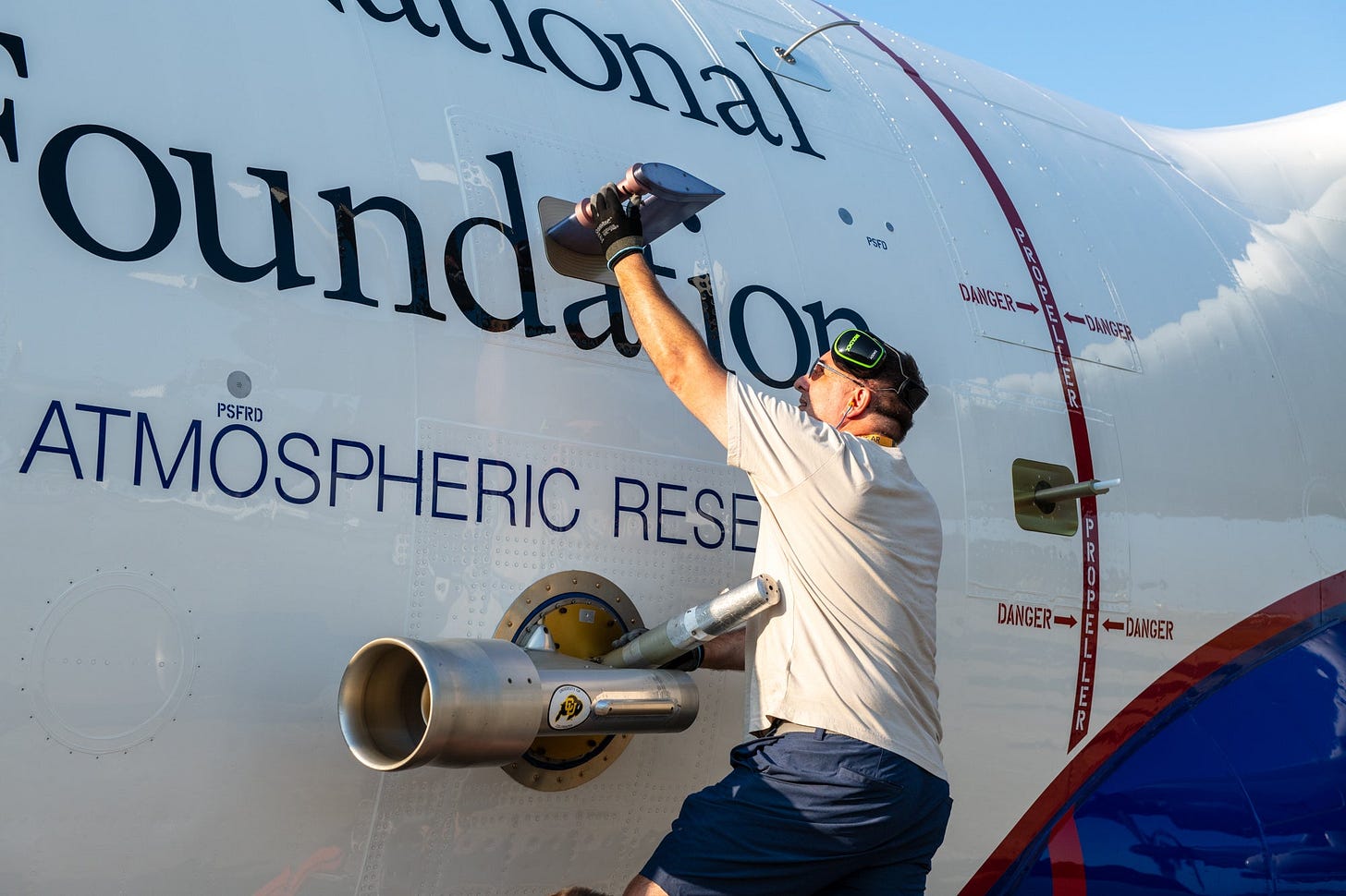 A technician performs maintenance on a instrument mounted on the outside of the aircraft.