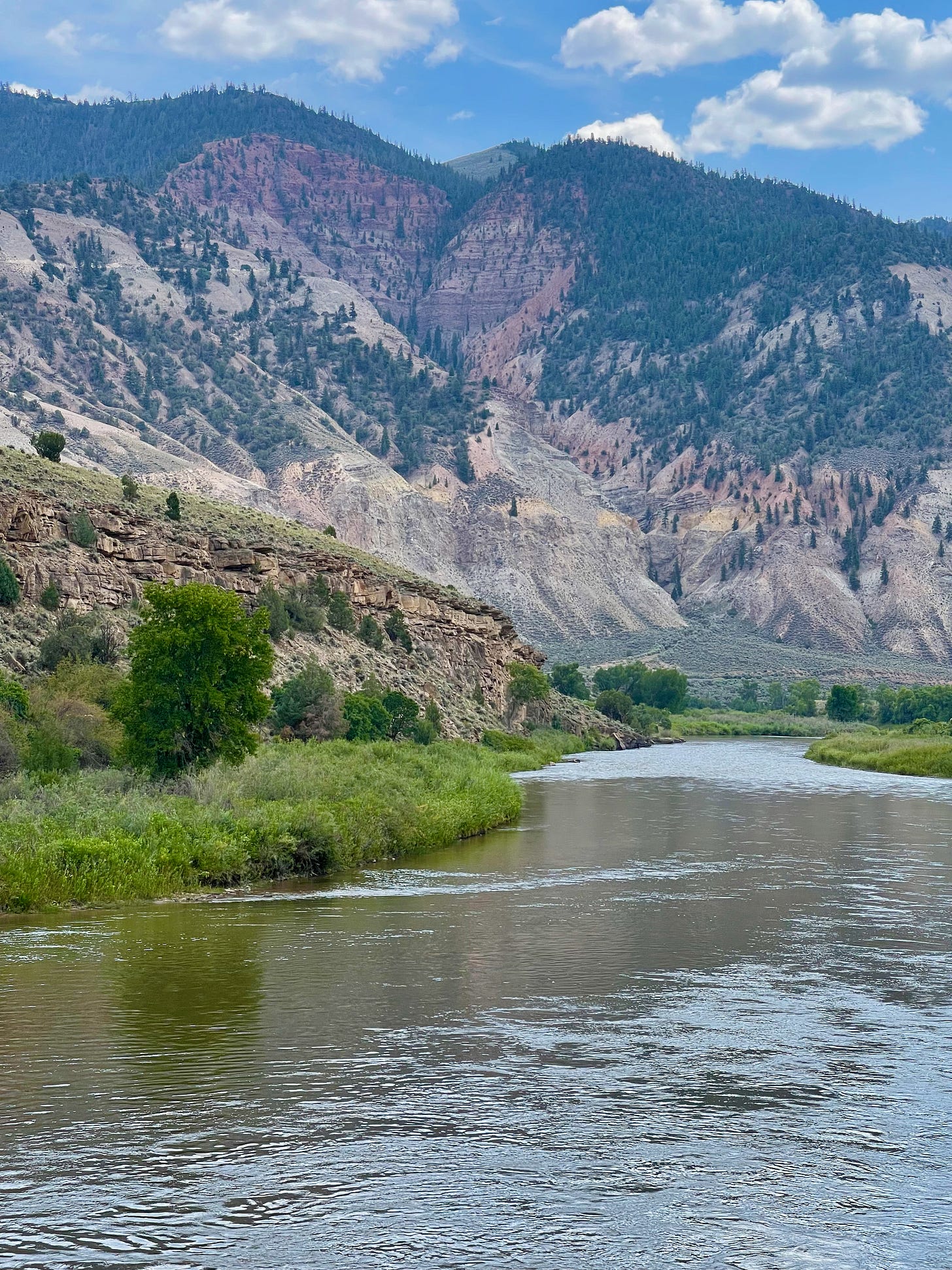 River with mountain in the background and a road cutting across the mountain face