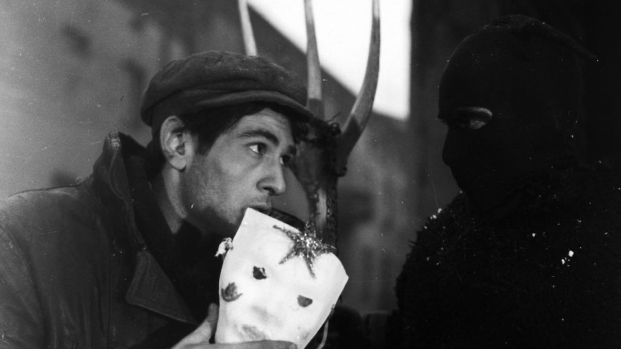 A nervous-looking Jakub (Serge Merlin) face to face with a reveller in costume.