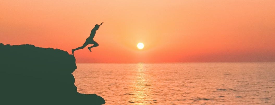 a person jumping off a cliff into the ocean