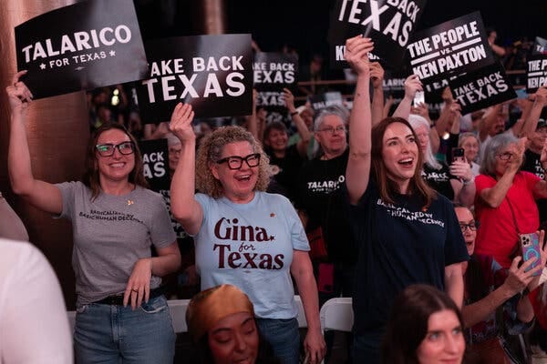 A group of smiling people hold up signs with slogans like “Talarico for Texas,” “Take back Texas” and “The people vs. Ken Paxton.” A group of smiling people hold up signs with slogans like “Talarico for Texas,” “Take back Texas” and “The people vs. Ken Paxton.”