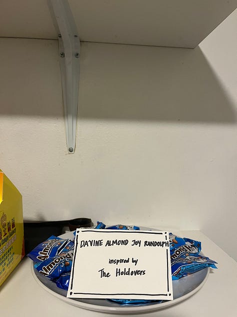 A dutch oven full of chili beside the label "Sloppenheimer," a stromboli behind a sign reading "Maestromboli," a plate of Almond Joys labeled "Da'Vine Almond Joy Randolph."