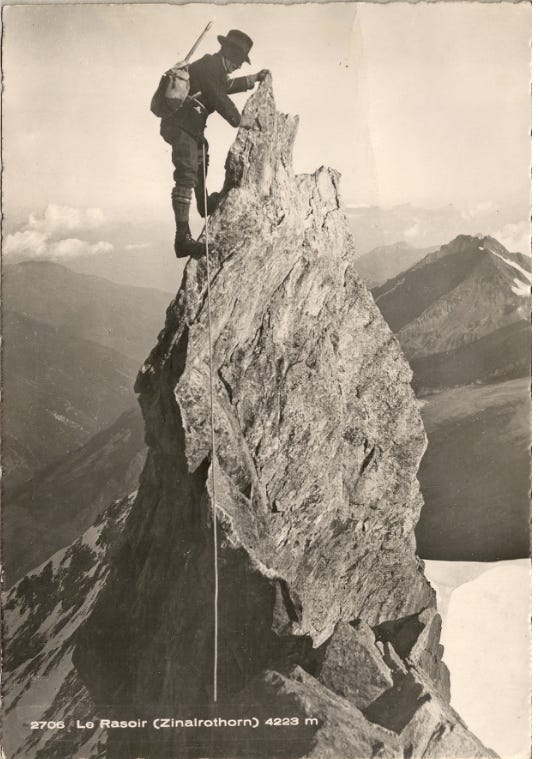 man in antique hat on pointy piece of rock. Big drops below