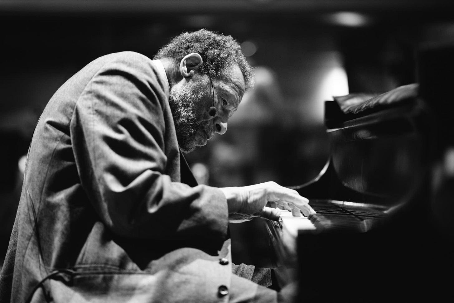 A black and white photograph of musician Cornbread Harris, a black elderly man, playing the piano