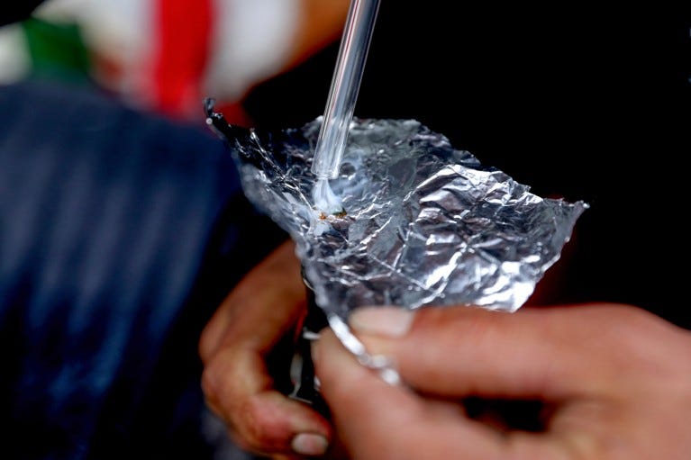 Close up of fentanyl being smoked off a piece of foil through a glass pipe
